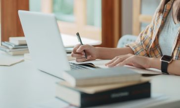 Young woman student busy study make notes in notebook and using