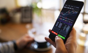Trading with cryptocurrency on smartphone and enjoying coffee.