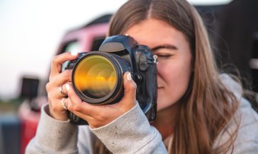 A young woman with a professional camera takes a photo in nature.